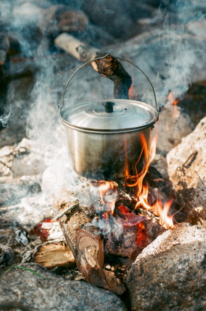 Une casserole entrain de chauffer au-dessus d'un feu de bois dans la nature