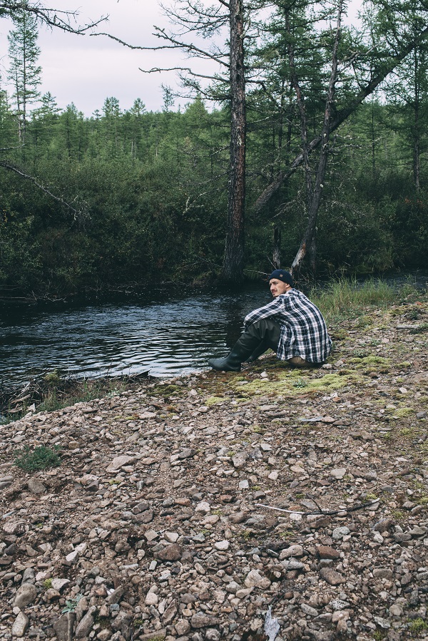 Homme assis au bord de la rivière avec des cuissardes